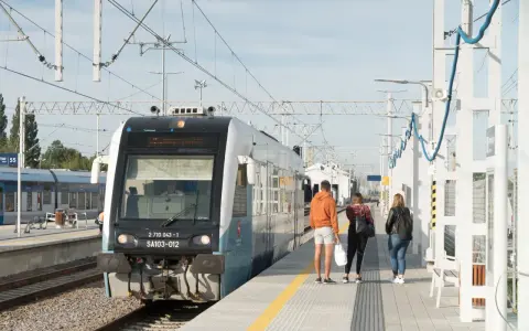 Pociąg na stacji z pasażerami czekającymi na peronie.