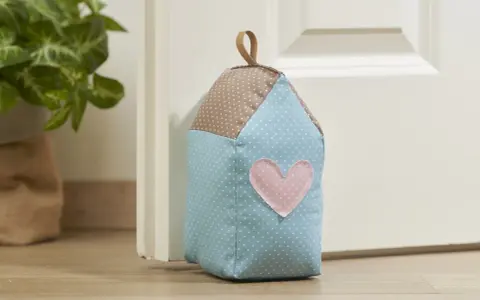 Un cale porte en tissu gratuit en forme de maison, avec un cœur rose. Parfait pour un **patron cale porte en tissu gratuit**.