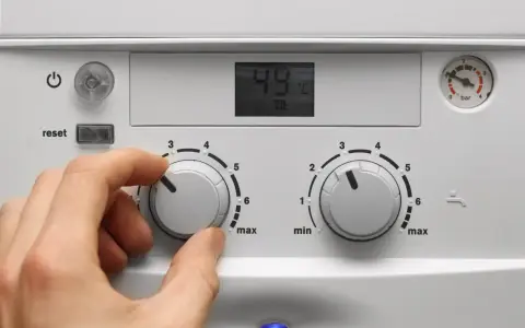 Mano che regola la caldaia spenta senza corrente. Il display mostra 49°C.