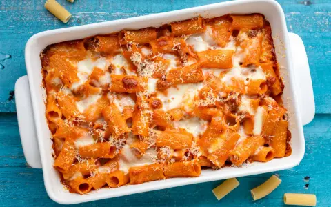 Un invitante piatto di pasta al forno con sugo rosso e formaggio filante, pronto per essere gustato.