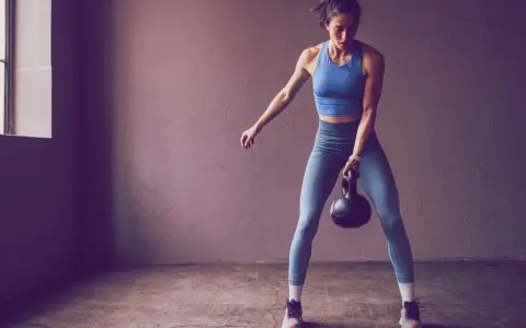 Frau trainiert mit Kettlebell, Teil der 75 Hard Challenge.