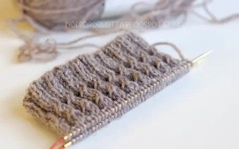 Knitted swatch with textured pattern and yarn on needles.