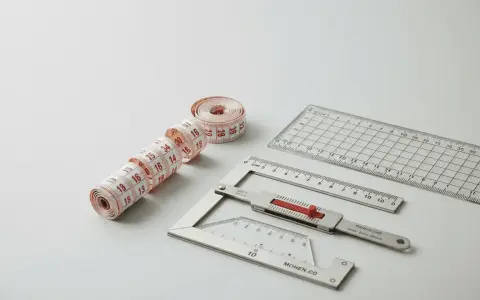 Ruban de couture nervuré et règles de précision, outils essentiels pour des mesures parfaites.
