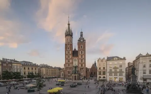 Majestatyczna Bazylika Mariacka góruje nad Rynkiem Głównym w Krakowie. Tłumy spacerują, podziwiając architekturę i atmosferę miasta.