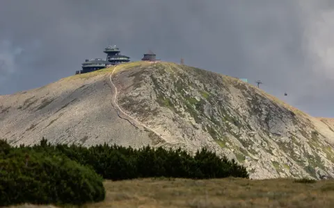 Schronisko i obserwatorium na szczycie w Karkonoszach, z widoczną kolejką linową i kamienistym zboczem.