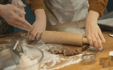 Mains farinées étalant une pâte à biscuits. Une question se pose : par quoi remplacer la farine de sarrasin pour une recette sans gluten ?