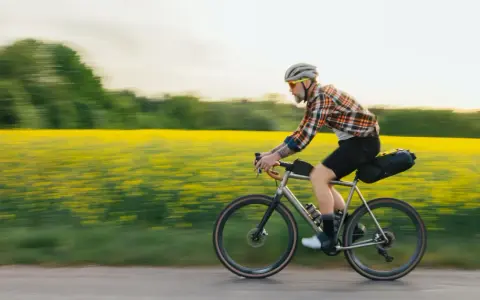 Man cyklar genom ett fält med gula blommor, en idyllisk vy över cykelleder Sverige.