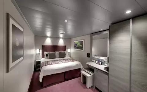 Cabina MSC Seaside, ponte 14: letto matrimoniale, specchio, armadio e un quadro decorativo.