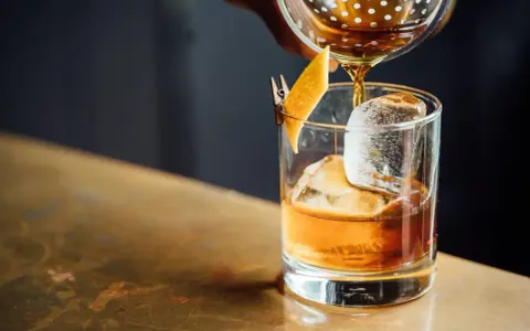 Whisky nalewana do szklanki z lodem i skórką pomarańczy.