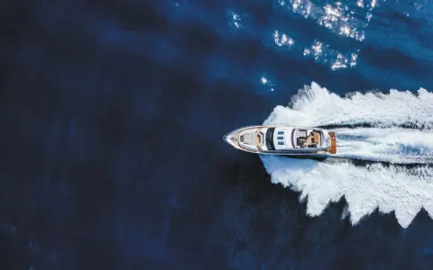 Un bateau hors-bord puissant fend les eaux bleues, laissant une traînée d'écume blanche derrière lui.