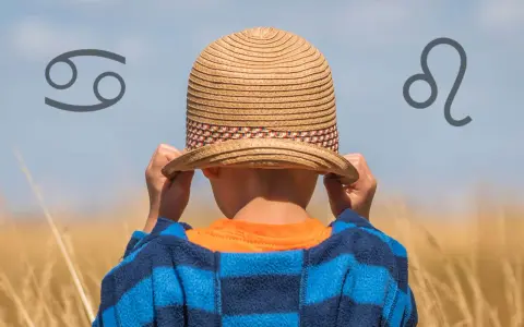Chłopiec w słomkowym kapeluszu, z symbolem Raka po lewej i Lwa po prawej. 28 lipiec znak zodiaku.