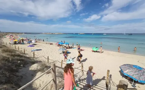 Giornata di sole a Formentera con bambini, tra sabbia bianca, mare cristallino e tante famiglie che si godono la vacanza.
