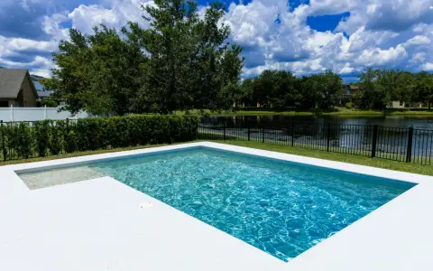 Agua de piscina blanquecina, cristalina y refrescante, con reflejos del cielo azul y nubes blancas. Un oasis de paz.