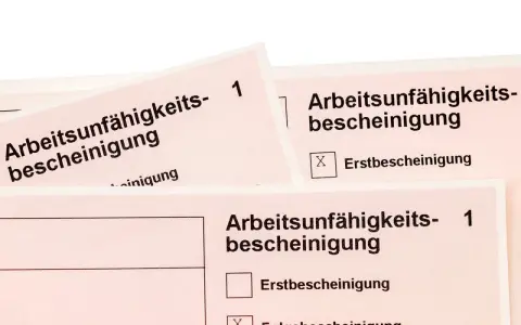 Arbeitsunfall krankschreibung unterbrochen: Mehrere Arbeitsunfähigkeitsbescheinigungen liegen übereinander. Eine Folgebescheinigung ist angekreuzt.