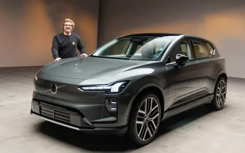 Ein Mann steht neben einem modernen, grauen Volvo EX90.