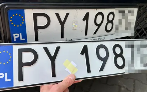 Dwie polskie tablice rejestracyjne PY 198. Jedna jest zamontowana na samochodzie, druga trzymana w ręku.