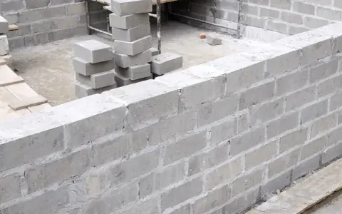 Budowa fundamentów z bloczków betonowych, stosy bloczków na placu budowy.