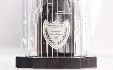 Dom Pérignon Vintage 2012 in einer modernen, transparenten Hülle mit dunklem Holzsockel.