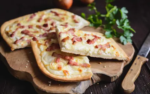 Flammekueche, une spécialité alsacienne d'origine, garnie de lardons et d'oignons sur une pâte fine.