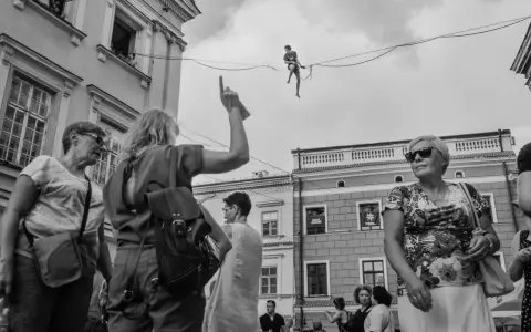 Street foto: tłum na ulicy obserwuje śmiałka balansującego na linie.