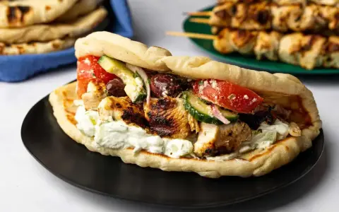 En saftig gyros med grillspett, tzatziki, tomat, gurka och oliver i pitabröd. Perfekt för ett snabbt grillspett recept.