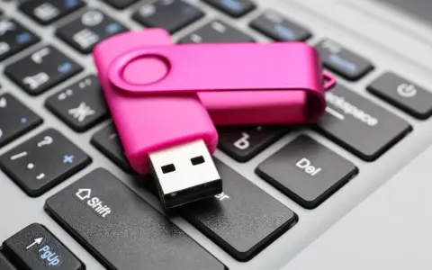 Różowy pendrive leży na klawiaturze, gotowy do pracy jak przenośny dysk twardy.