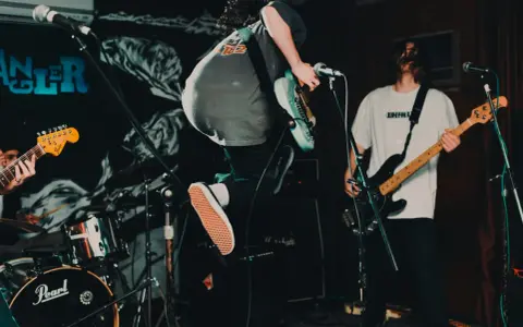 Ein Gitarrist springt auf der Bühne, während ein Bassist spielt. Das ist Rockmusik in Aktion!