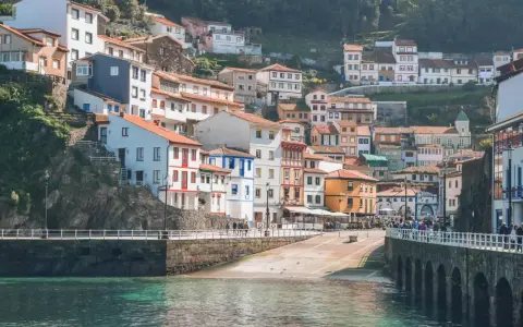 Casas de colores se aferran a la ladera en uno de los pueblos con encanto en Asturias, con el mar turquesa al frente.