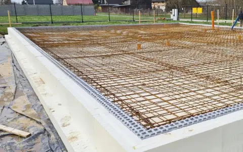 Siatka zbrojenia na fundamencie z białych bloczków styropianowych, gotowa do zalania betonem.