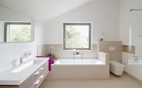 Salle de bain moderne avec baignoire, lavabo, douche vitrée et toilette suspendue.