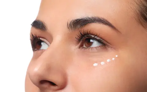 Application de crème hydratante sous les yeux, parfaite pour le maquillage hivernal.
