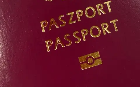 Ciemnoczerwony paszport z napisem "PASZPORT" i symbolem. Numer paszportu jest ukryty.