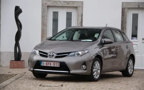 Szary Toyota Auris 1.6 benzyna, idealny do miasta, z niskim spalaniem. Obok rzeźba.