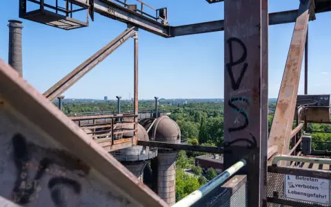 Industrielles Erbe in Duisburg: Rostige Stahlkonstruktionen und Kuppeln des Landschaftsparks Nord, mit Blick auf grüne Bäume und Gebäude.