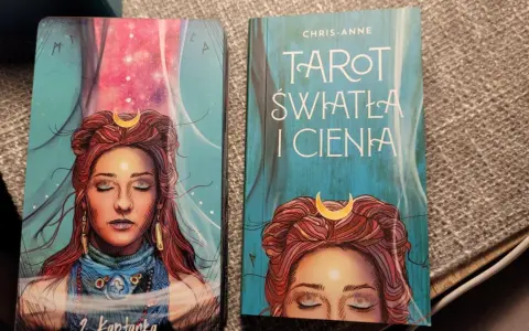 Karty i książka "Tarot Światła i Cienia" z wizerunkiem kobiety z księżycem na czole.