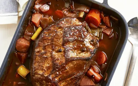 Herzhaftes Rinderbratenstück in dunkler Sauce mit Karotten und Lauch, perfekt für festliche Schmorgerichte an Weihnachten.