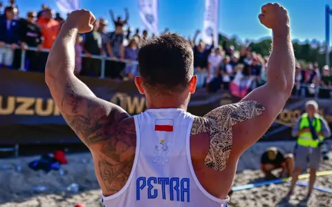 Hubert Wolski, z podniesionymi rękami, świętuje zwycięstwo. Na koszulce widnieje godło Polski i napis "PETRA".