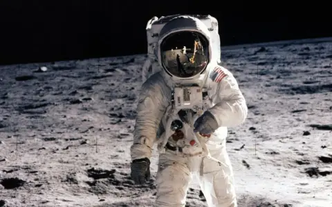 Un astronaute sur la Lune, le 20 juillet 1969. Le reflet dans son casque montre la Terre et d'autres astronautes.