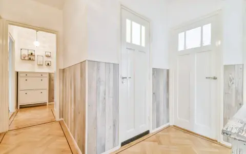 Stara boazeria w nowej odsłonie – panele imitujące drewno nadają korytarzowi nowoczesny charakter.