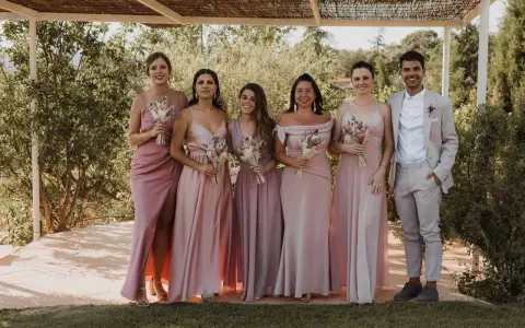Grupo de damas de honor y el novio posando para una foto en una boda informal campo.