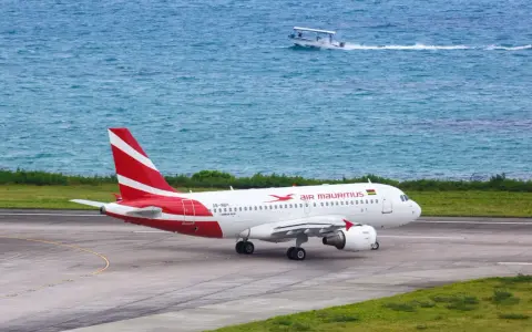 Samolot Air Mauritius na pasie startowym, w tle turkusowe morze i łódź. Twoje loty na Mauritius właśnie się zaczynają!