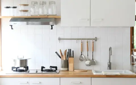 Diseños de cocinas pequeñas y sencillas: encimera de madera, campana extractora, utensilios colgados y un fregadero blanco.
