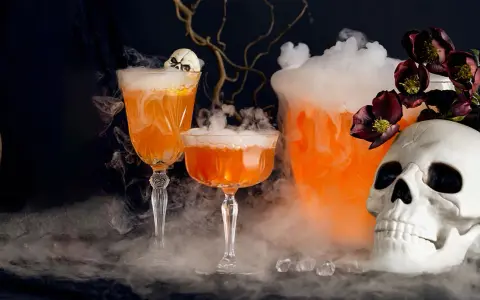 Två orangea drinkar med skum och en dödskalle, perfekt för en kuslig halloween-kväll.