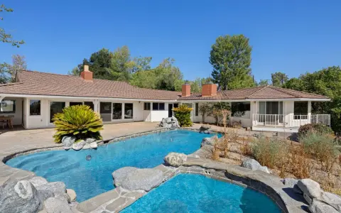 La piscina e il giardino di una casa che ricorda lo stile del **Kim Kardashian house**, con un'architettura moderna e un'area esterna rilassante.