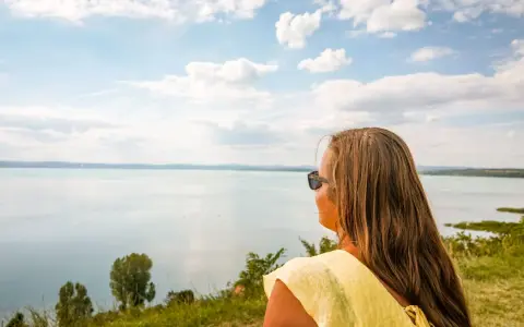 Kobieta w żółtej bluzce podziwia widok na Balaton. Wspaniałe chmury na niebie, idealne miejsce, gdzie nad Balaton.