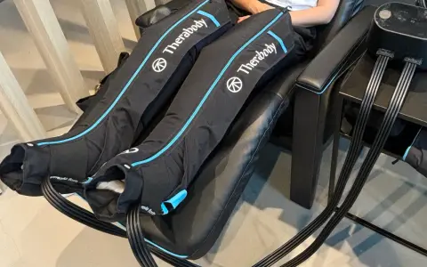 Are leg compression massagers good for you? This image shows a person using Therabody recovery boots, which are leg compression massagers, for a relaxing massage.