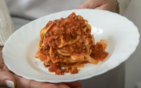 Un piatto di tagliatelle al ragù, un classico della cucina italiana, servito su un piatto bianco.