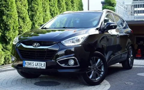 Czarny Hyundai ix35 2.0 benzyna + LPG, lśniący na podjeździe przed zielonym żywopłotem.
