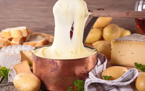 Fondue au fromage, un délice des spécialités culinaires auvergnates, avec du pain, des pommes de terre et du vin rouge.
