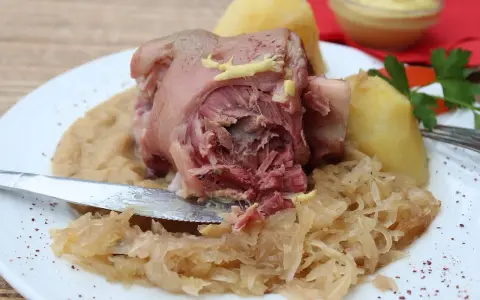 Un plat copieux de spécialités culinaires alsaciennes : jarret de porc, purée de pommes de terre et choucroute, garni de moutarde.